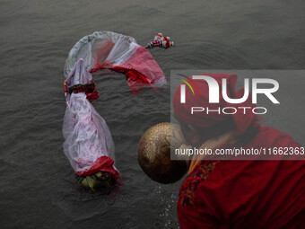 Bangladeshi Hindu devotees immerse an idol of their deity Durga into the Buriganga River during the last day of the Durga Puja, the largest...