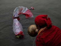 Bangladeshi Hindu devotees immerse an idol of their deity Durga into the Buriganga River during the last day of the Durga Puja, the largest...