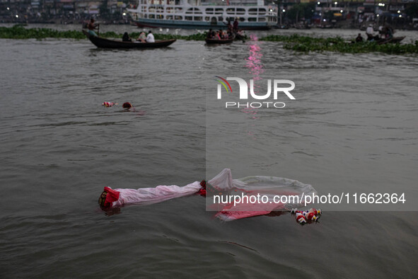 Bangladeshi Hindu devotees immerse an idol of their deity Durga into the Buriganga River during the last day of the Durga Puja, the largest...