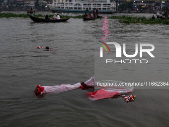 Bangladeshi Hindu devotees immerse an idol of their deity Durga into the Buriganga River during the last day of the Durga Puja, the largest...