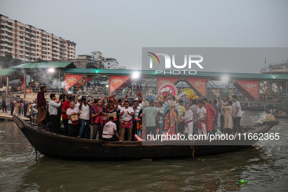 Bangladeshi Hindu devotees immerse an idol of their deity Durga into the Buriganga River during the last day of the Durga Puja, the largest...