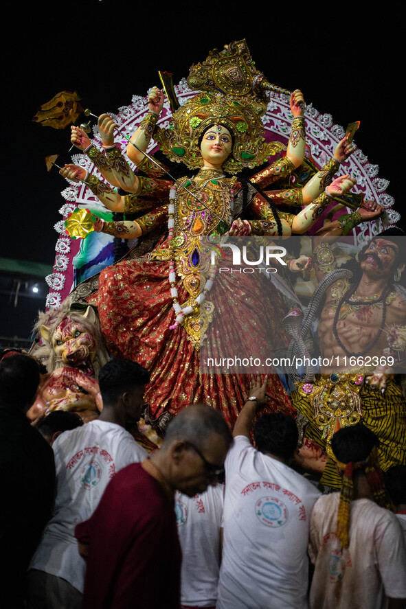 Bangladeshi Hindu devotees immerse an idol of their deity Durga into the Buriganga River during the last day of the Durga Puja, the largest...