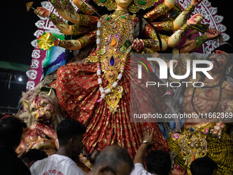 Bangladeshi Hindu devotees immerse an idol of their deity Durga into the Buriganga River during the last day of the Durga Puja, the largest...