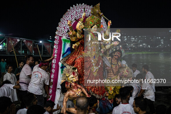 Bangladeshi Hindu devotees immerse an idol of their deity Durga into the Buriganga River during the last day of the Durga Puja, the largest...