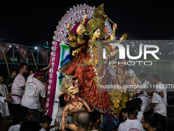 Bangladeshi Hindu devotees immerse an idol of their deity Durga into the Buriganga River during the last day of the Durga Puja, the largest...