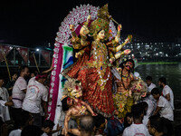 Bangladeshi Hindu devotees immerse an idol of their deity Durga into the Buriganga River during the last day of the Durga Puja, the largest...