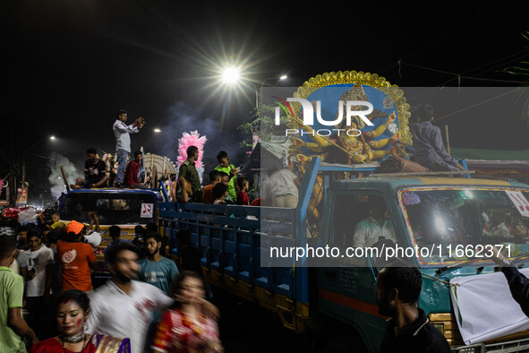 Bangladeshi Hindu devotees immerse an idol of their deity Durga into the Buriganga River during the last day of the Durga Puja, the largest...