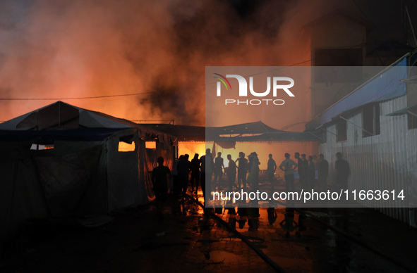 People attempt to extinguish a fire at the site of an Israeli strike on tents sheltering displaced people amid the Israel-Hamas conflict in...