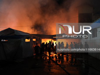 People attempt to extinguish a fire at the site of an Israeli strike on tents sheltering displaced people amid the Israel-Hamas conflict in...