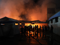 People attempt to extinguish a fire at the site of an Israeli strike on tents sheltering displaced people amid the Israel-Hamas conflict in...