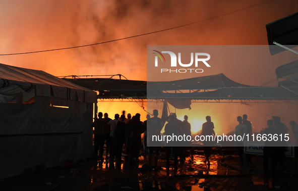 People attempt to extinguish a fire at the site of an Israeli strike on tents sheltering displaced people amid the Israel-Hamas conflict in...