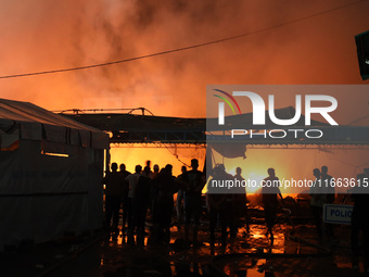 People attempt to extinguish a fire at the site of an Israeli strike on tents sheltering displaced people amid the Israel-Hamas conflict in...