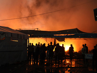 People attempt to extinguish a fire at the site of an Israeli strike on tents sheltering displaced people amid the Israel-Hamas conflict in...