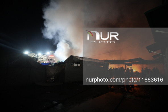 People attempt to extinguish a fire at the site of an Israeli strike on tents sheltering displaced people amid the Israel-Hamas conflict in...