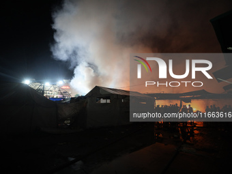 People attempt to extinguish a fire at the site of an Israeli strike on tents sheltering displaced people amid the Israel-Hamas conflict in...