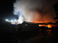 People attempt to extinguish a fire at the site of an Israeli strike on tents sheltering displaced people amid the Israel-Hamas conflict in...