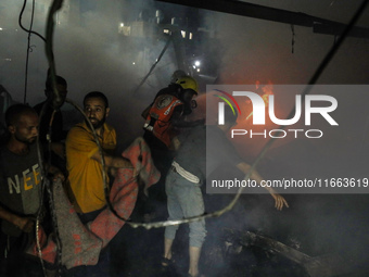 People attempt to extinguish a fire at the site of an Israeli strike on tents sheltering displaced people amid the Israel-Hamas conflict in...