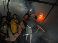 People attempt to extinguish a fire at the site of an Israeli strike on tents sheltering displaced people amid the Israel-Hamas conflict in...