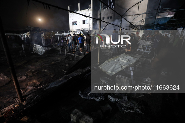 People attempt to extinguish a fire at the site of an Israeli strike on tents sheltering displaced people amid the Israel-Hamas conflict in...