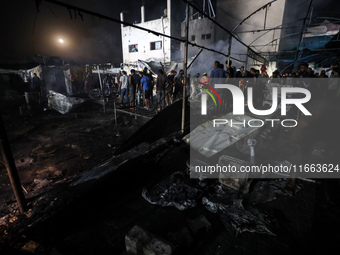 People attempt to extinguish a fire at the site of an Israeli strike on tents sheltering displaced people amid the Israel-Hamas conflict in...