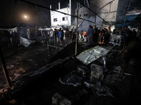 People attempt to extinguish a fire at the site of an Israeli strike on tents sheltering displaced people amid the Israel-Hamas conflict in...