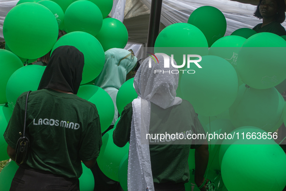 Volunteers hold ceremonial green balloons, symbolizing hope and resilience in the face of mental health challenges, during the launch of the...