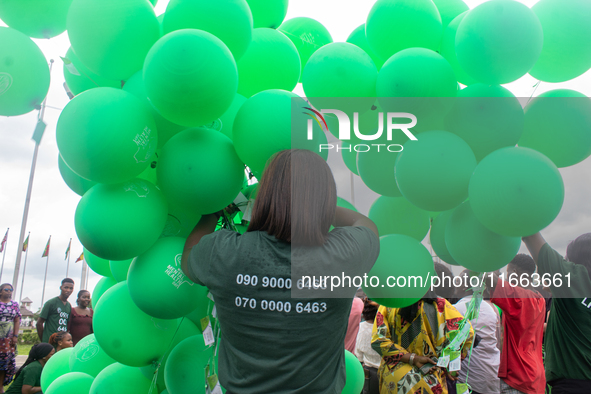 A volunteer holds ceremonial green balloons, symbolizing hope and resilience in the face of mental health challenges, during the launch of t...