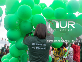 A volunteer holds ceremonial green balloons, symbolizing hope and resilience in the face of mental health challenges, during the launch of t...