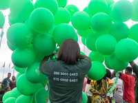 A volunteer holds ceremonial green balloons, symbolizing hope and resilience in the face of mental health challenges, during the launch of t...