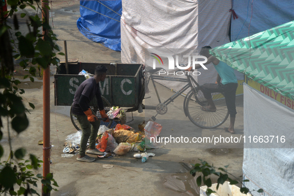 Workers clean the ground premises in the early morning where visitors have thrown waste at a ground where the Durga Puja Fair is set up in S...