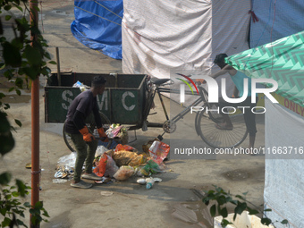 Workers clean the ground premises in the early morning where visitors have thrown waste at a ground where the Durga Puja Fair is set up in S...