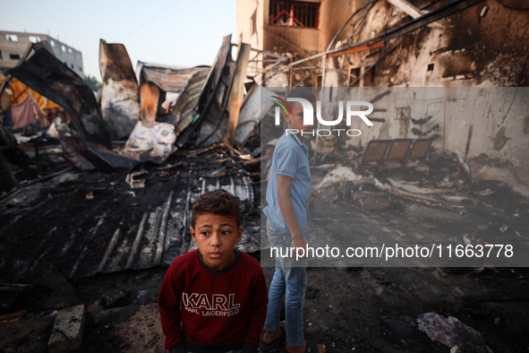 Palestinians survey the damage at the site of an Israeli strike on tents sheltering displaced people at Al-Aqsa Martyrs hospital in Deir Al-...