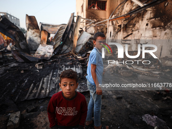 Palestinians survey the damage at the site of an Israeli strike on tents sheltering displaced people at Al-Aqsa Martyrs hospital in Deir Al-...