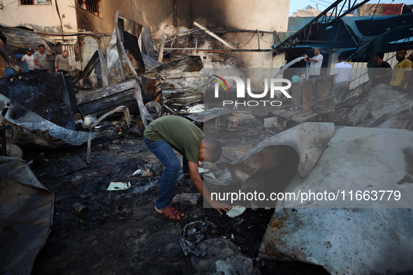 Palestinians survey the damage at the site of an Israeli strike on tents sheltering displaced people at Al-Aqsa Martyrs hospital in Deir Al-...