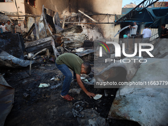 Palestinians survey the damage at the site of an Israeli strike on tents sheltering displaced people at Al-Aqsa Martyrs hospital in Deir Al-...