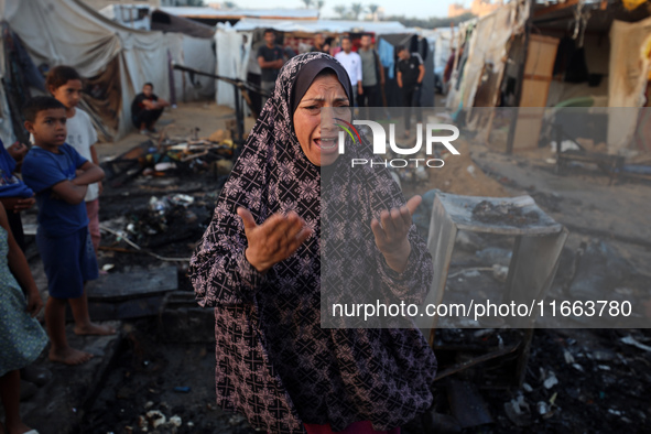 A Palestinian woman observes the site of an Israeli strike on tents sheltering displaced people, amid the Israel-Hamas conflict, at Al-Aqsa...