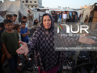 A Palestinian woman observes the site of an Israeli strike on tents sheltering displaced people, amid the Israel-Hamas conflict, at Al-Aqsa...