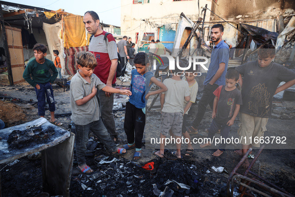 Palestinians survey the damage at the site of an Israeli strike on tents sheltering displaced people at Al-Aqsa Martyrs hospital in Deir Al-...