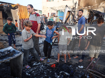 Palestinians survey the damage at the site of an Israeli strike on tents sheltering displaced people at Al-Aqsa Martyrs hospital in Deir Al-...