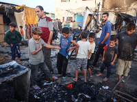 Palestinians survey the damage at the site of an Israeli strike on tents sheltering displaced people at Al-Aqsa Martyrs hospital in Deir Al-...