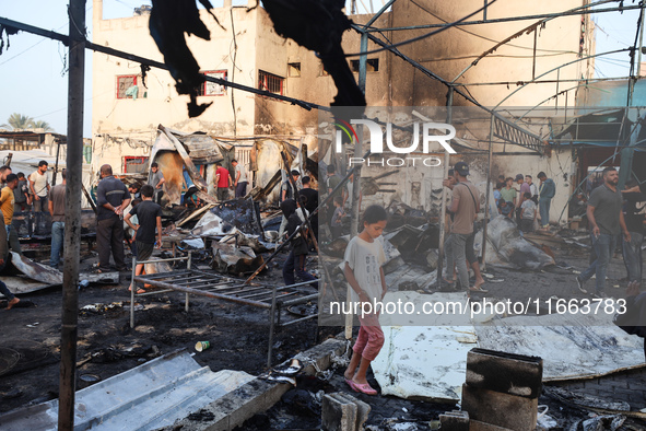 Palestinians survey the damage at the site of an Israeli strike on tents sheltering displaced people at Al-Aqsa Martyrs hospital in Deir Al-...