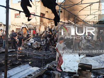 Palestinians survey the damage at the site of an Israeli strike on tents sheltering displaced people at Al-Aqsa Martyrs hospital in Deir Al-...