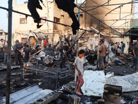 Palestinians survey the damage at the site of an Israeli strike on tents sheltering displaced people at Al-Aqsa Martyrs hospital in Deir Al-...