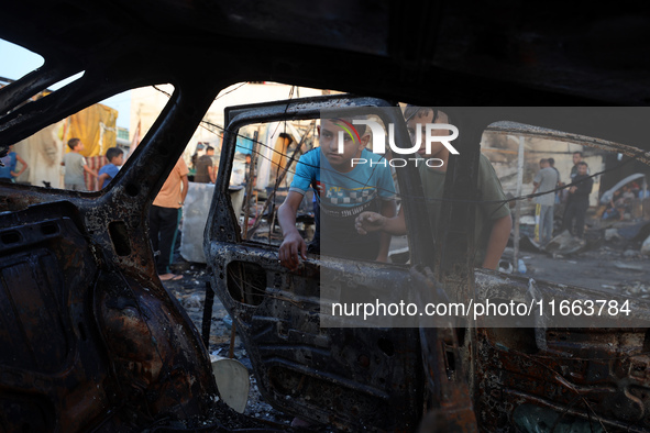 Palestinians survey the damage at the site of an Israeli strike on tents sheltering displaced people at Al-Aqsa Martyrs hospital in Deir Al-...