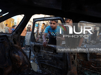 Palestinians survey the damage at the site of an Israeli strike on tents sheltering displaced people at Al-Aqsa Martyrs hospital in Deir Al-...