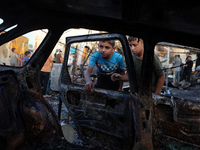 Palestinians survey the damage at the site of an Israeli strike on tents sheltering displaced people at Al-Aqsa Martyrs hospital in Deir Al-...