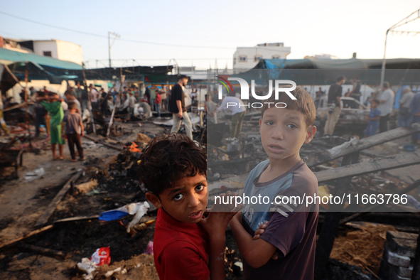 Palestinians survey the damage at the site of an Israeli strike on tents sheltering displaced people at Al-Aqsa Martyrs hospital in Deir Al-...