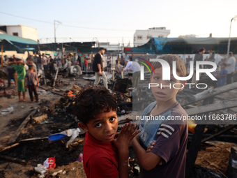 Palestinians survey the damage at the site of an Israeli strike on tents sheltering displaced people at Al-Aqsa Martyrs hospital in Deir Al-...