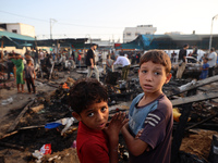 Palestinians survey the damage at the site of an Israeli strike on tents sheltering displaced people at Al-Aqsa Martyrs hospital in Deir Al-...