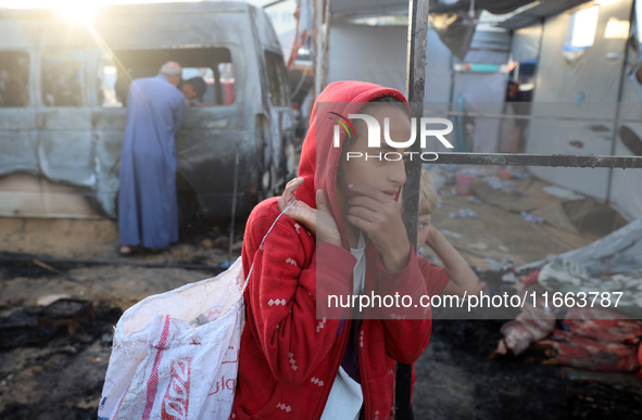 Palestinians survey the damage at the site of an Israeli strike on tents sheltering displaced people at Al-Aqsa Martyrs hospital in Deir Al-...